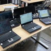 Seven MNT Reform laptops on a table together in a hackerspace